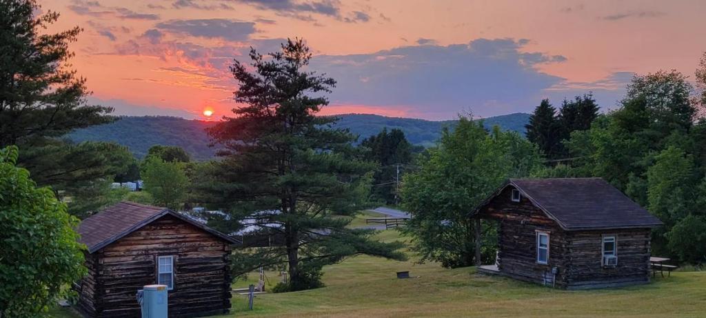 deux vieux bâtiments dans un champ avec le coucher de soleil en arrière-plan dans l'établissement Lake Lauderdale Campground, à Cambridge