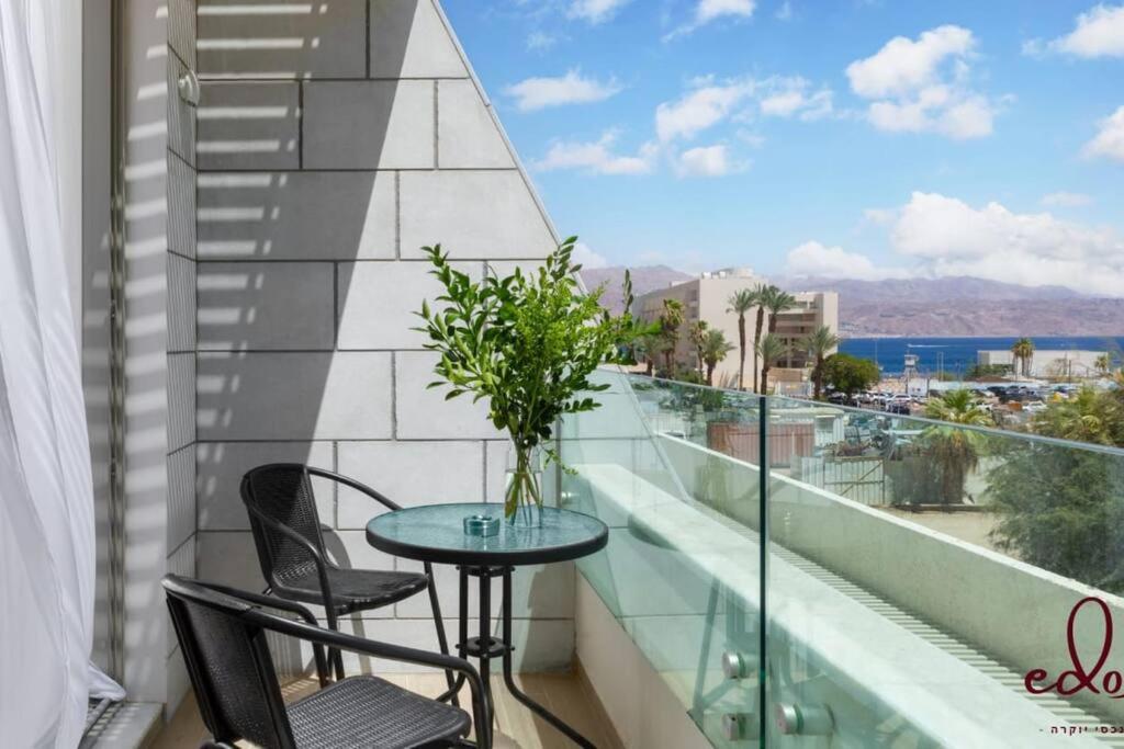 a balcony with a table and chairs and a view of the ocean at דירה יוקרתית 100 מטר מהים - By Edomlux in Eilat