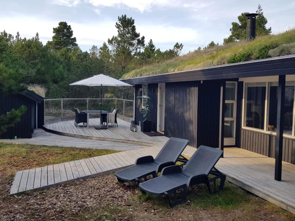 a house with two chairs and an umbrella on a deck at Holiday home Nørre Nebel LXXXIV in Nørre Nebel