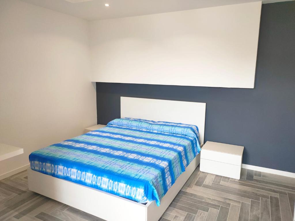 Schlafzimmer mit einem Bett mit einer blauen und weißen Bettdecke in der Unterkunft Stanza idromassaggio 2 in Quartu SantʼElena