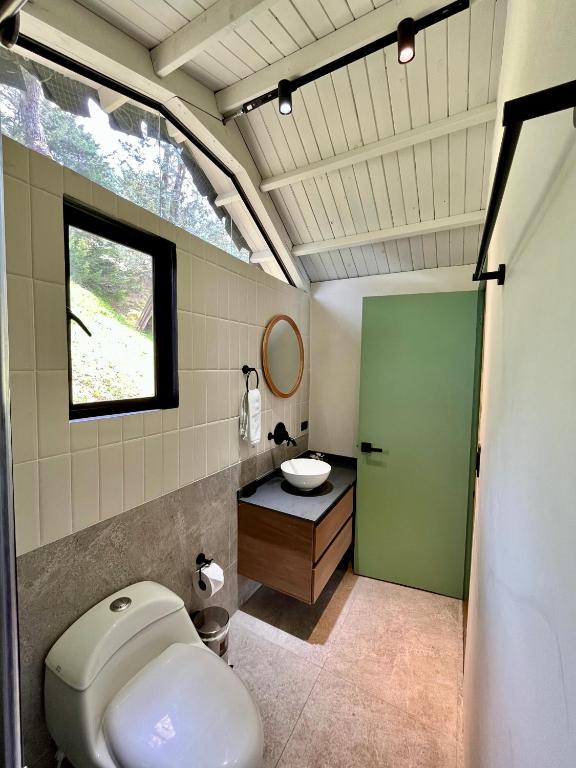 a bathroom with a toilet and a sink and a window at Soy Local Guatape in Guatapé