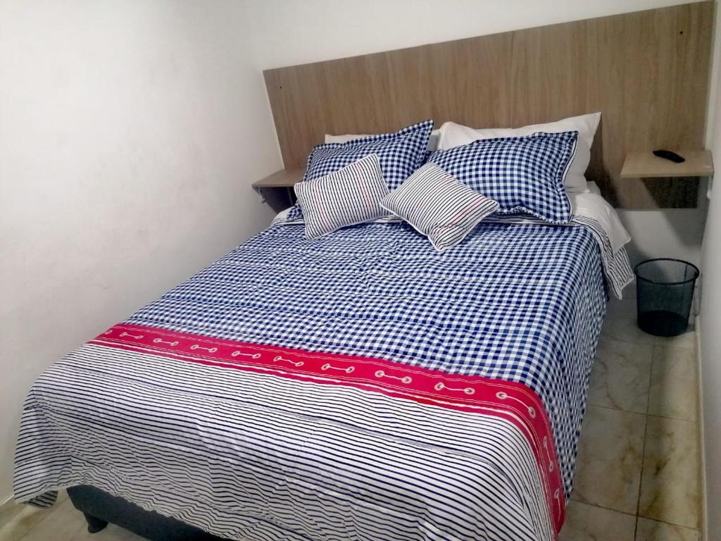 a bed with blue and white sheets and pillows at Casa Hospedaje - H in Bogotá