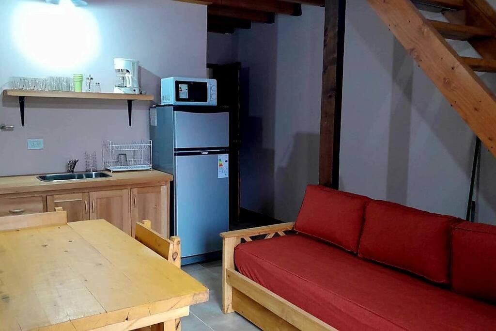 cocina con sofá rojo y nevera azul en Cabaña en Villa Los Coihues en San Carlos de Bariloche
