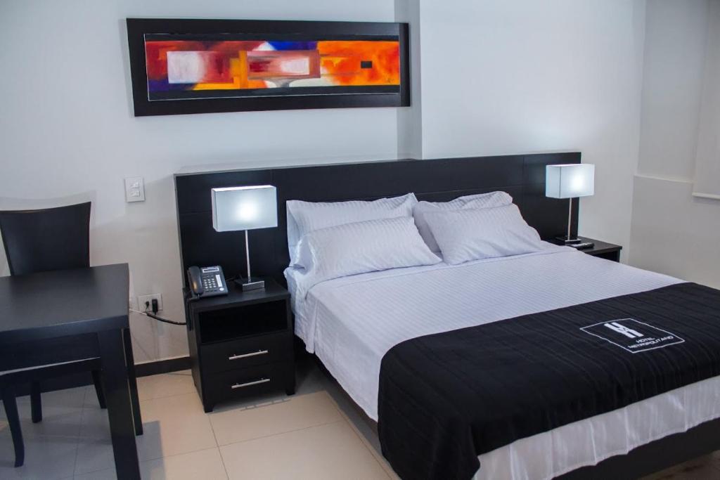 Hotel Metropolitano في نيفا: غرفة نوم بسرير ومكتب فيه مصباحين