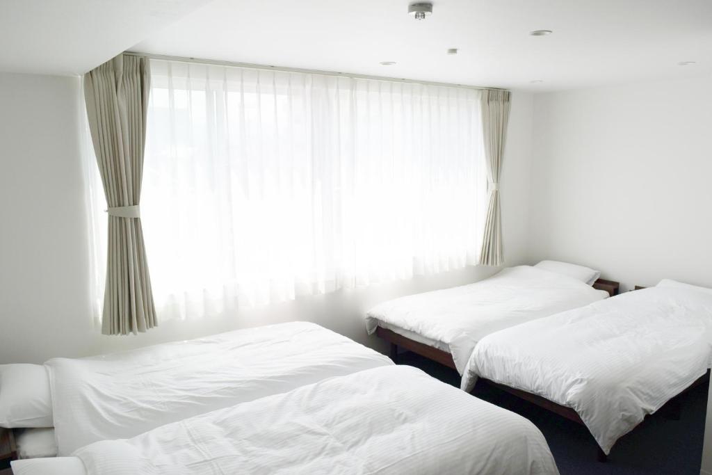 two beds in a room with a window at Center Point In Kanazawa in Kanazawa