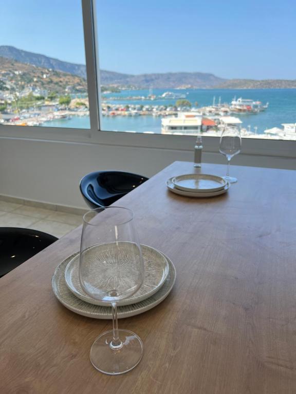 two wine glasses sitting on a wooden table with a view at Elounda Port Apartment in Elounda