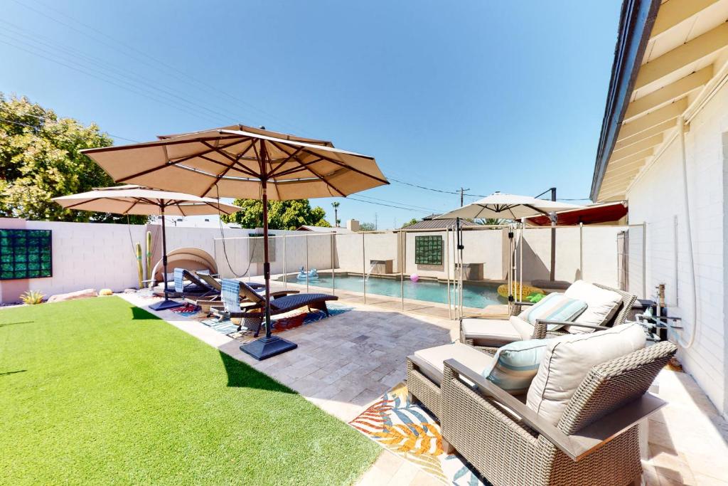 斯科茨代爾的住宿－Cozy Casa on Coronado，一个带椅子和遮阳伞的庭院和一个游泳池