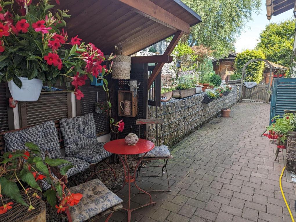 a patio with a table and chairs and flowers at Herzstuecke-Ferienwohnung in Ingenried