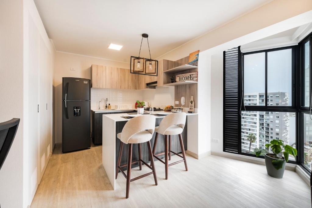 a kitchen with a black refrigerator and stools at Barranco inolvidable BR1 in Lima