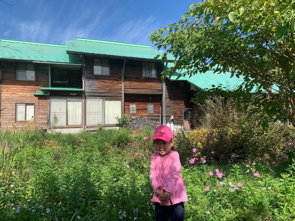 a little girl standing in front of a house at ペンションminiモンゴル in Makito