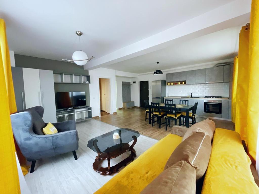 sala de estar con sofá amarillo y mesa en YamaLuxe Apartments - WestSide 2, en Floreşti