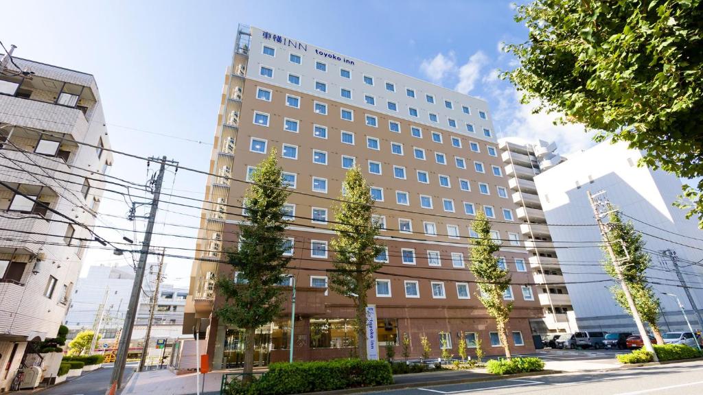 a large building on a street with trees in front of it at Toyoko Inn Tokyo Keio-sen Higashi-fuchu-eki Kita-guchi in Fuchu