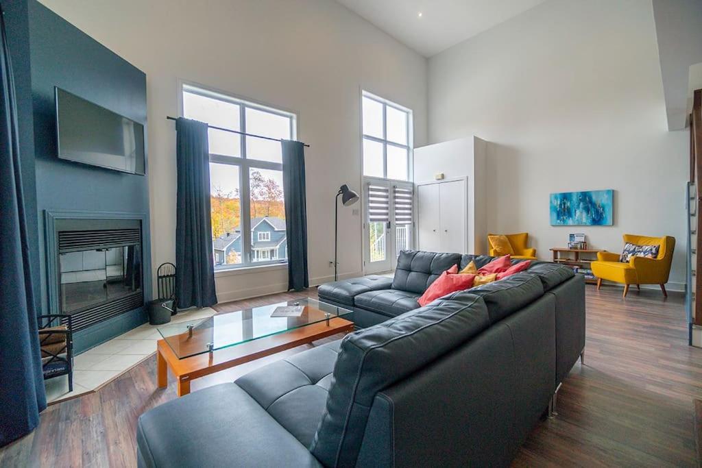 ein Wohnzimmer mit einem Sofa und einem Kamin in der Unterkunft Grands Espaces Orford 115 condo/chalet in Orford