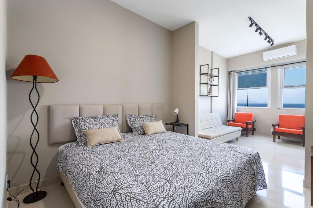 um quarto com uma cama, um candeeiro e uma cadeira em Atlântica Palace Vista Mar no Rio de Janeiro