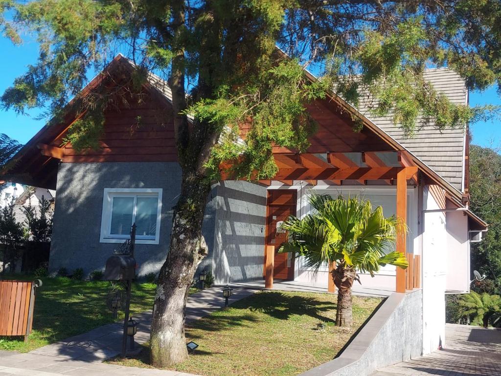 una casa con un árbol delante de ella en Hospedagem Jardins de Gramado, en Gramado