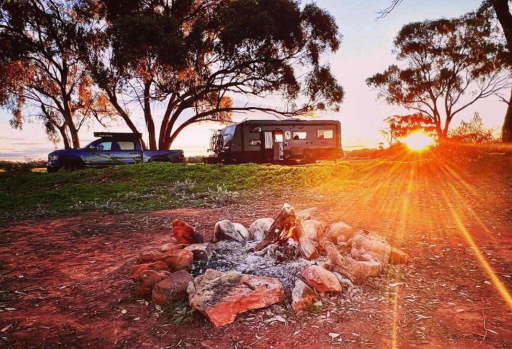 a camp fire with the sun setting in the background at Meralda Station in Cobar
