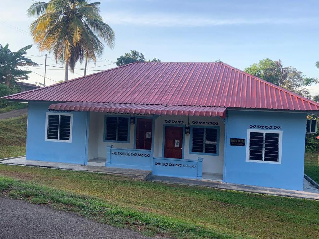 a small blue building with a red roof at Sarifah homestay in Melaka