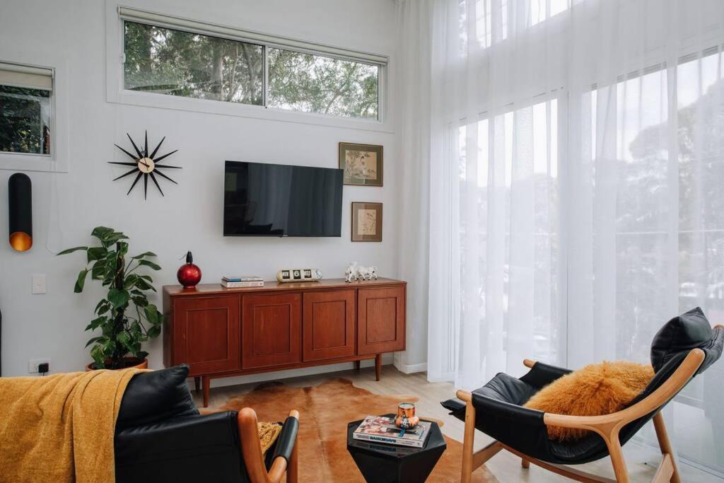 a living room with a tv and a couch and chairs at Retro Retreat - by Coast Hosting in Terrigal