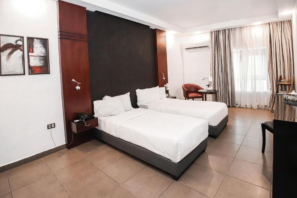 ein Hotelzimmer mit 2 Betten und einem Stuhl in der Unterkunft Torino Hotel Amman in Amman