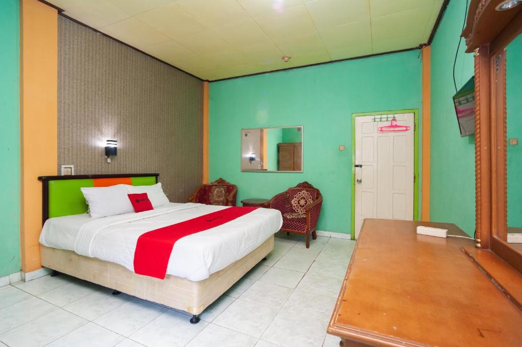 a bedroom with a large bed with green and orange walls at Reddoorz Syariah At Hotel Matahari 2 in Jambi
