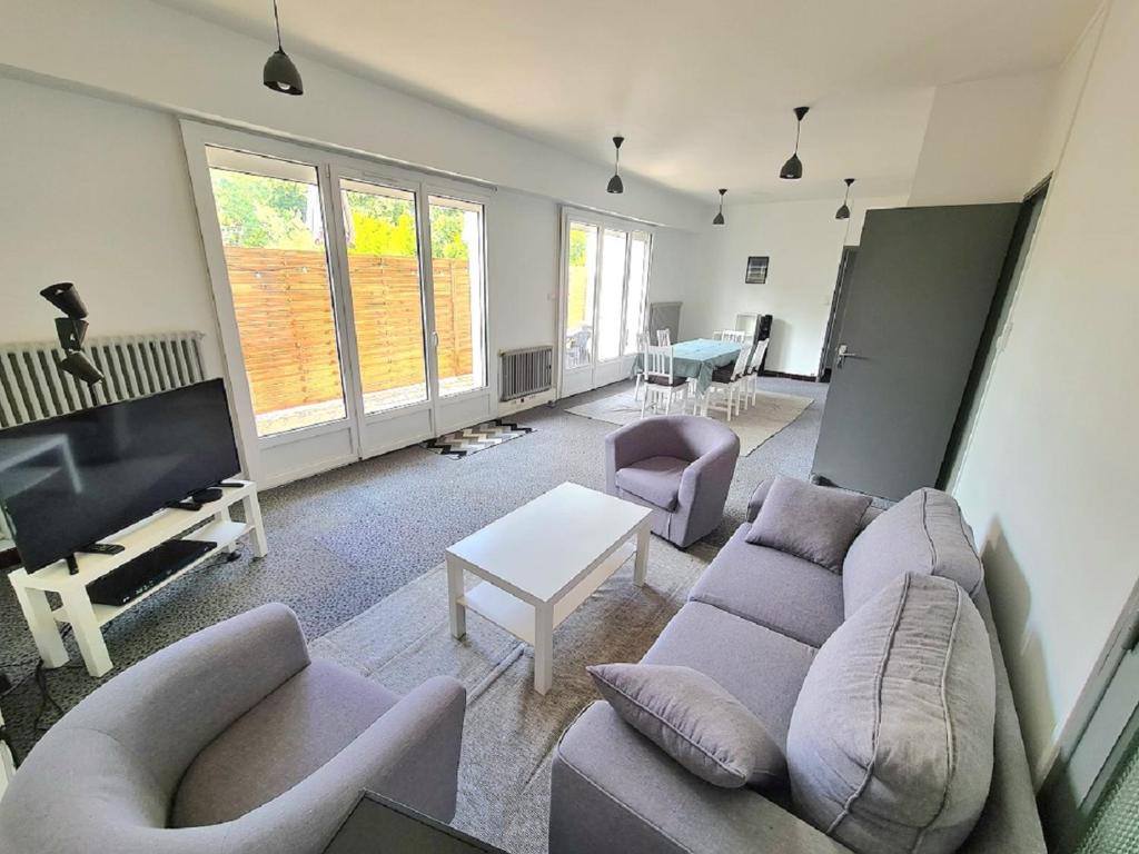 uma sala de estar com um sofá e cadeiras e uma televisão em Aigue Marine et Coquelicot em Jonzac