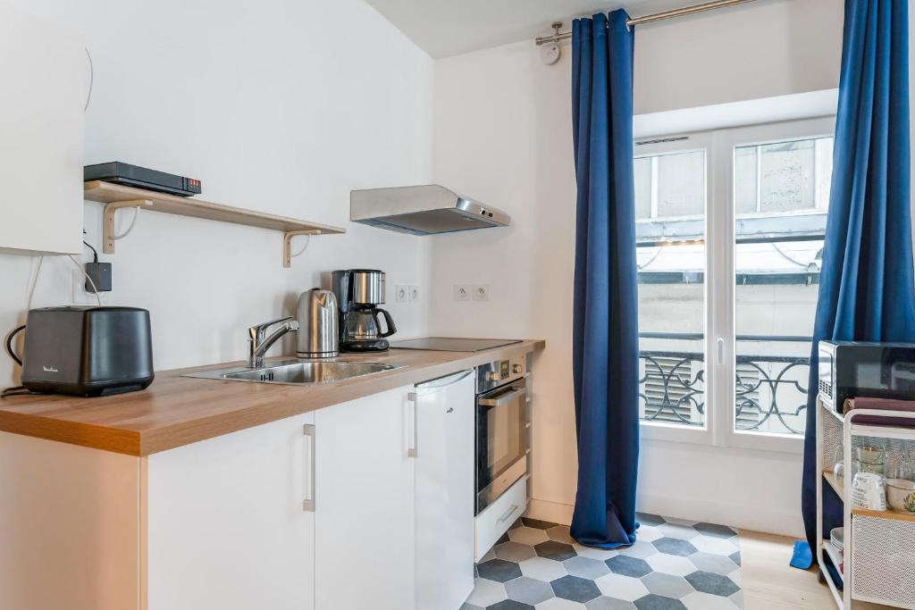 a small kitchen with a sink and a window at Renovated studio in the 6th district of Paris - Welkeys in Paris