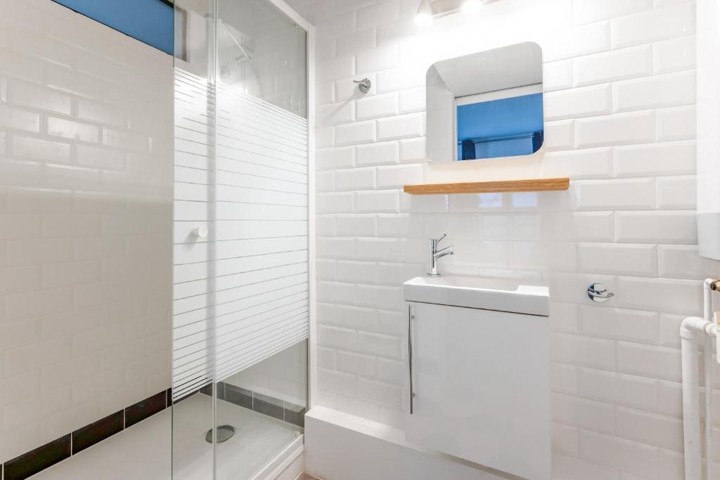 a white bathroom with a sink and a shower at Renovated studio in the 6th district of Paris - Welkeys in Paris
