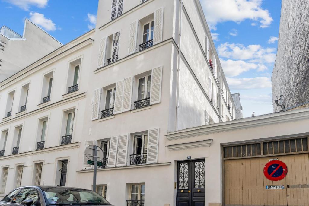a white building with a car parked in front of it at Renovated studio in the 6th district of Paris - Welkeys in Paris