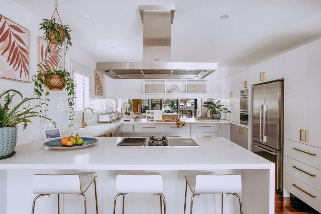 a white kitchen with a large white island with bar stools at Jungle Cubby - by Coast Hosting in Terrigal