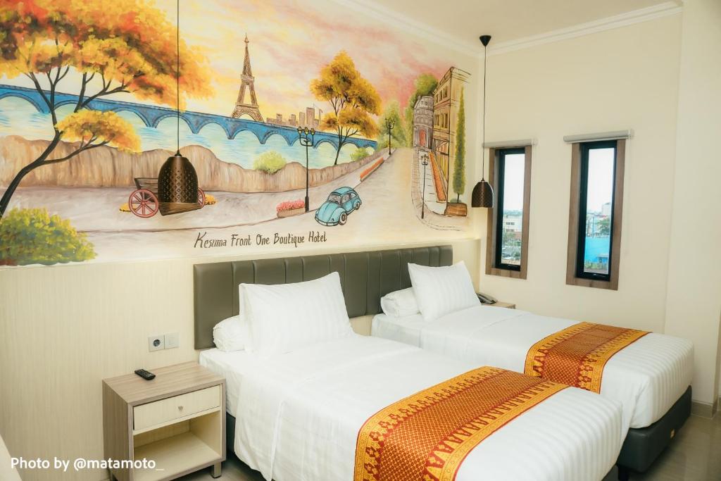 two beds in a room with a painting on the wall at Kesuma Front One Boutique Palembang in Palembang