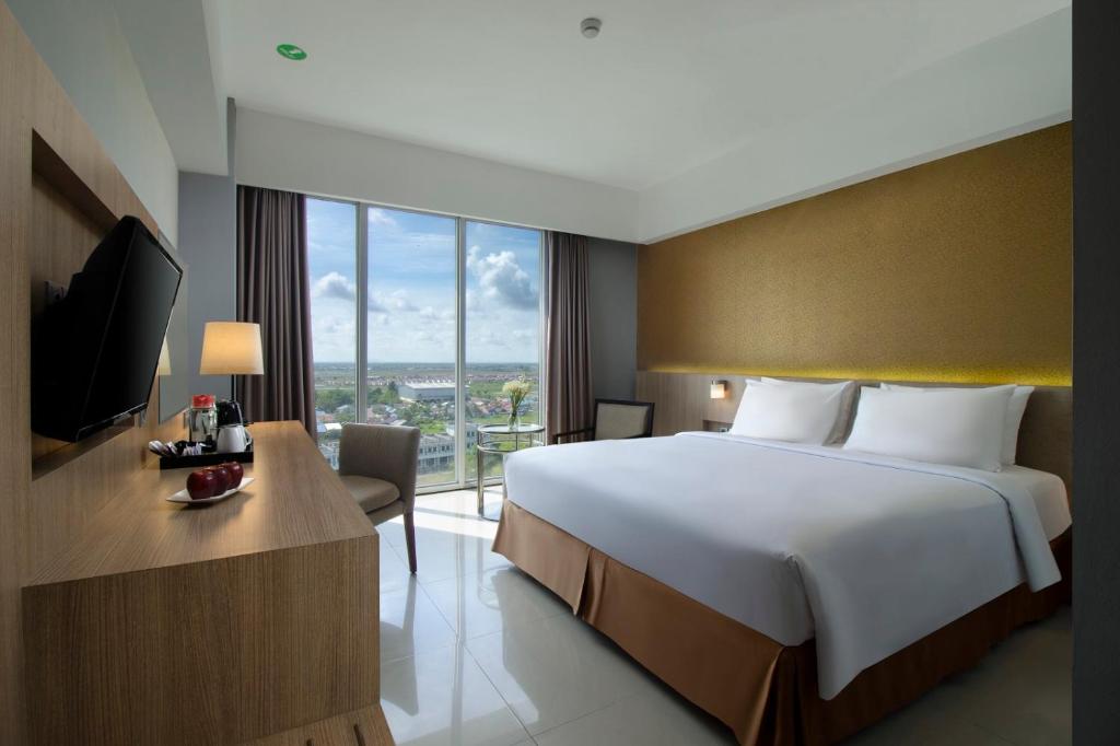 um quarto de hotel com uma cama grande e uma televisão em ASTON Banua Banjarmasin Hotel & Convention Center em Banjarmasin