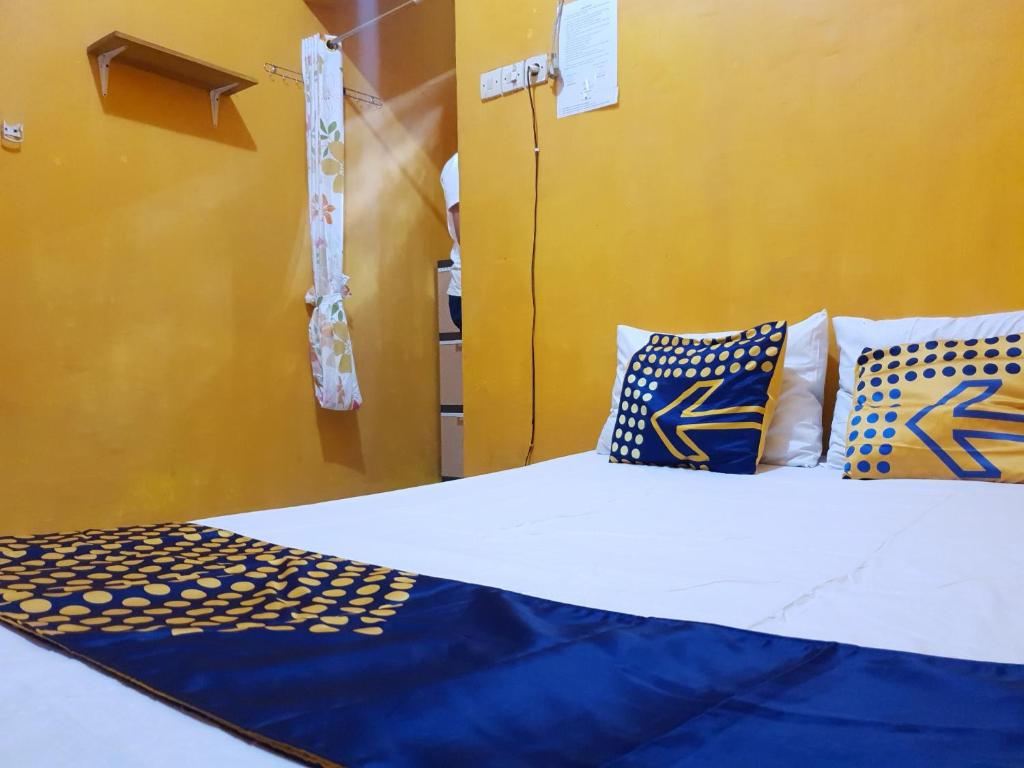 a bed with blue and yellow pillows in a room at SPOT ON 92857 Kos Haji Jakfar Syariah in Banyuwangi