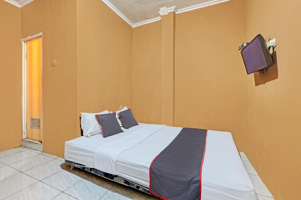 um quarto com uma cama e uma televisão na parede em Collection O 92864 Mitra Residence em Semarang