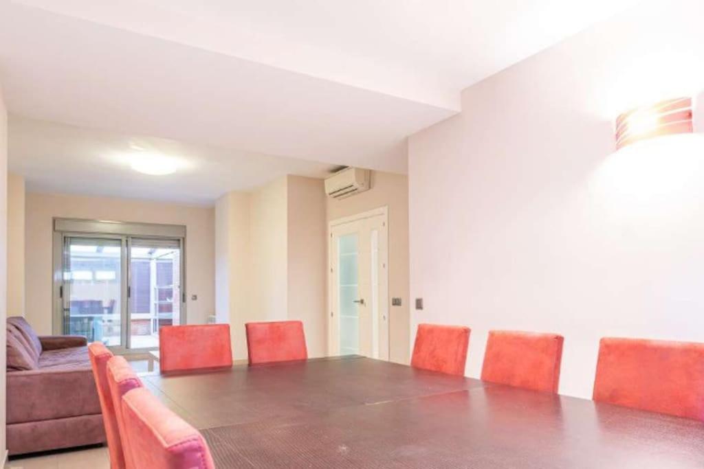 a dining room with a long table and red chairs at Impresionante apartamento de 4 dormitorios 3 baños y 2 plazas de garaje in Madrid