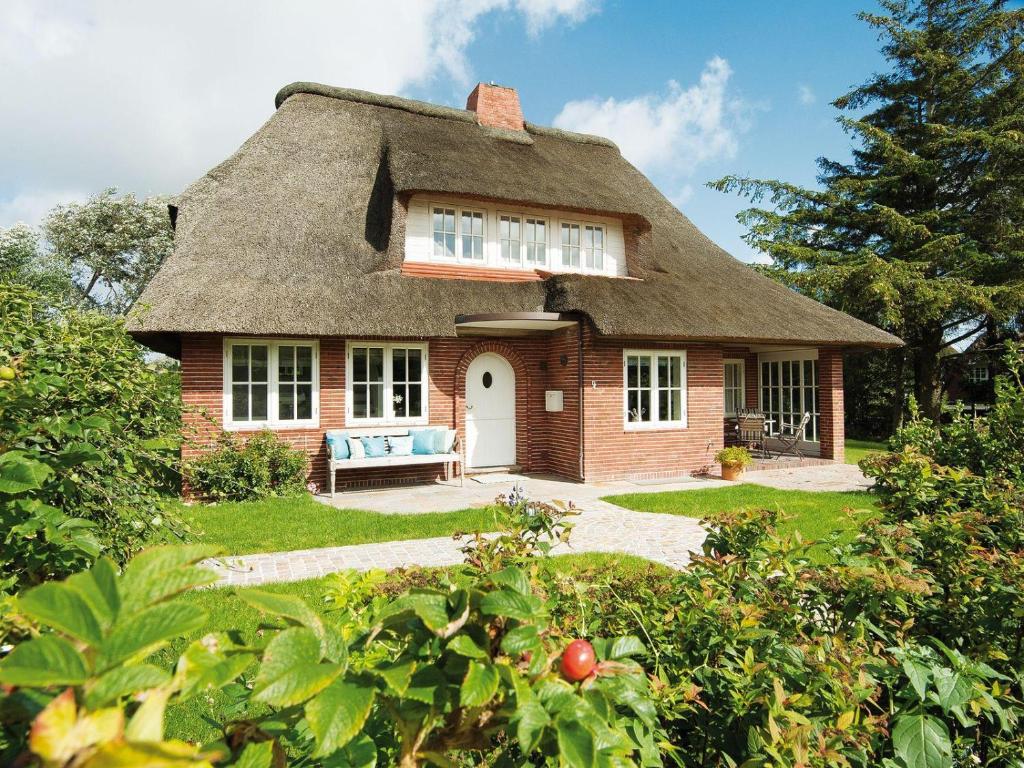 a thatch roofed house with a bench in the yard at Min-Go in Kampen