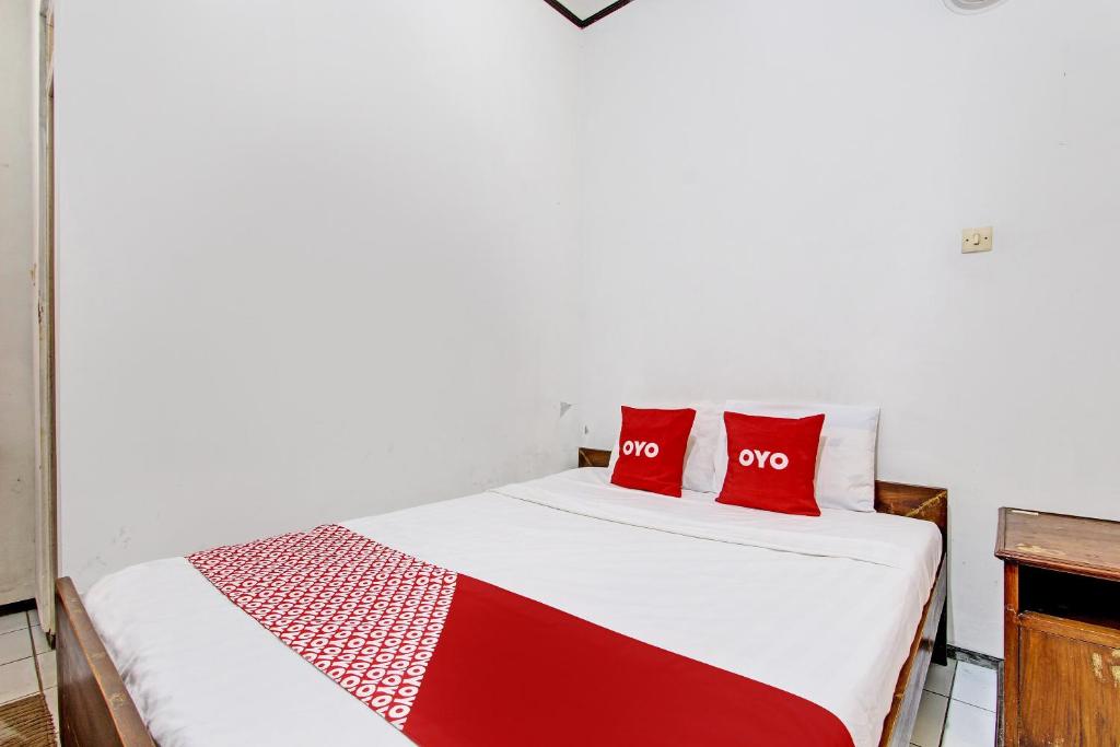 a bedroom with a bed with two red pillows at OYO 92885 Satriafi 2 Hotel in Yogyakarta