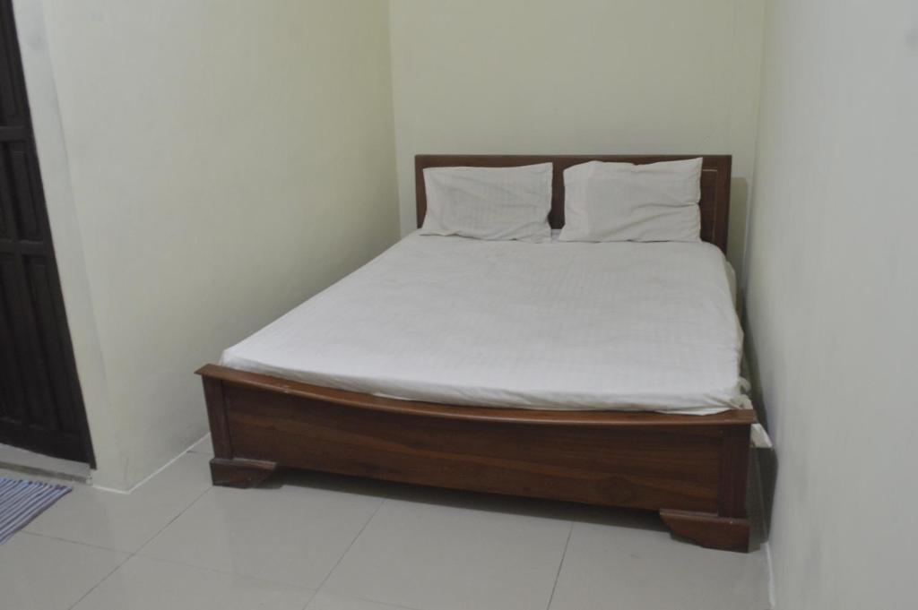 Bett mit weißer Bettwäsche und Kissen in einem Zimmer in der Unterkunft OYO 92880 Wisma Nusantara in Manado