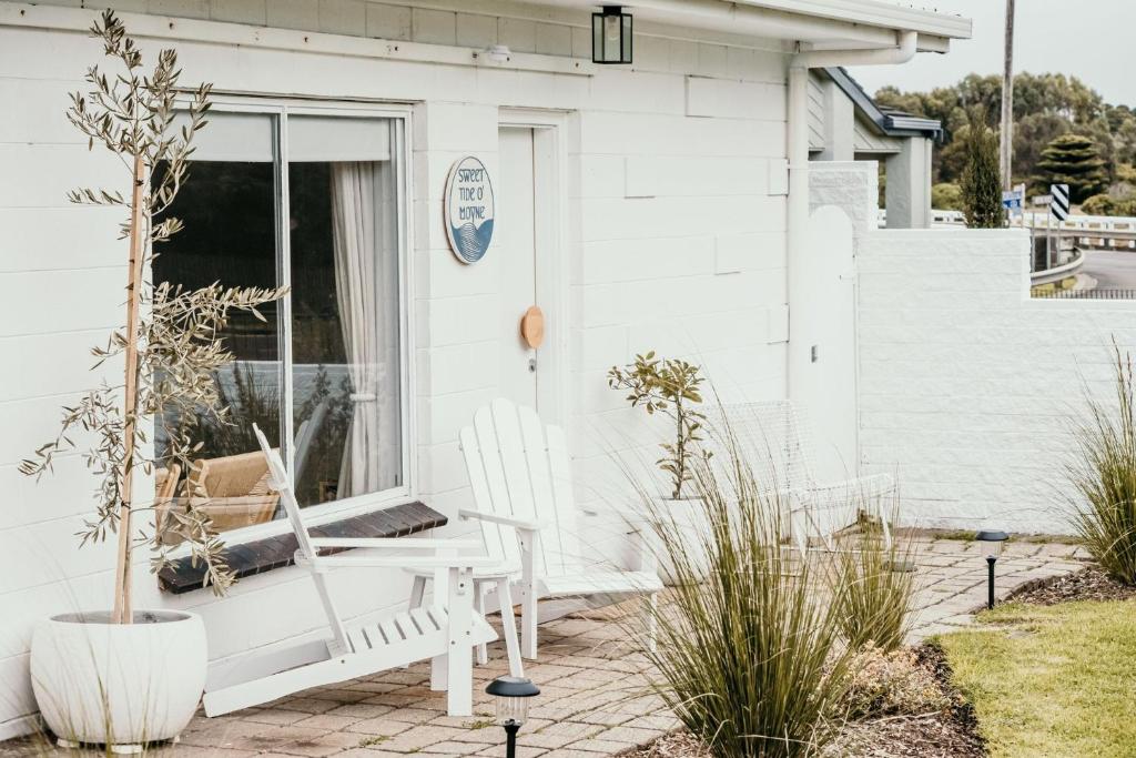 ein weißes Haus mit einem weißen Stuhl auf einer Terrasse in der Unterkunft Sweet Tide O Moyne in Port Fairy