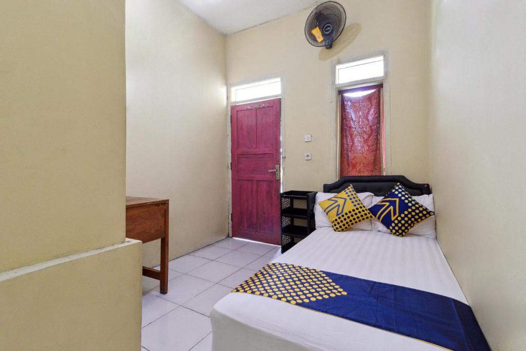 1 dormitorio con 1 cama y puerta roja en SPOT ON 92832 Al Mahira Syariah, en Majalengka