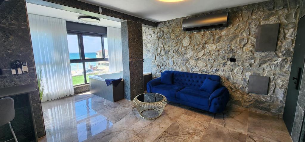 a blue couch in a room with a stone wall at מבנים בים 77 Suites at sea in Haifa