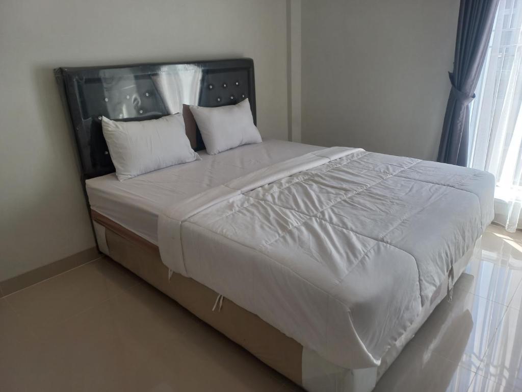 a bed with white sheets and pillows in a bedroom at OYO 92879 Imperial Inn in Cilacap