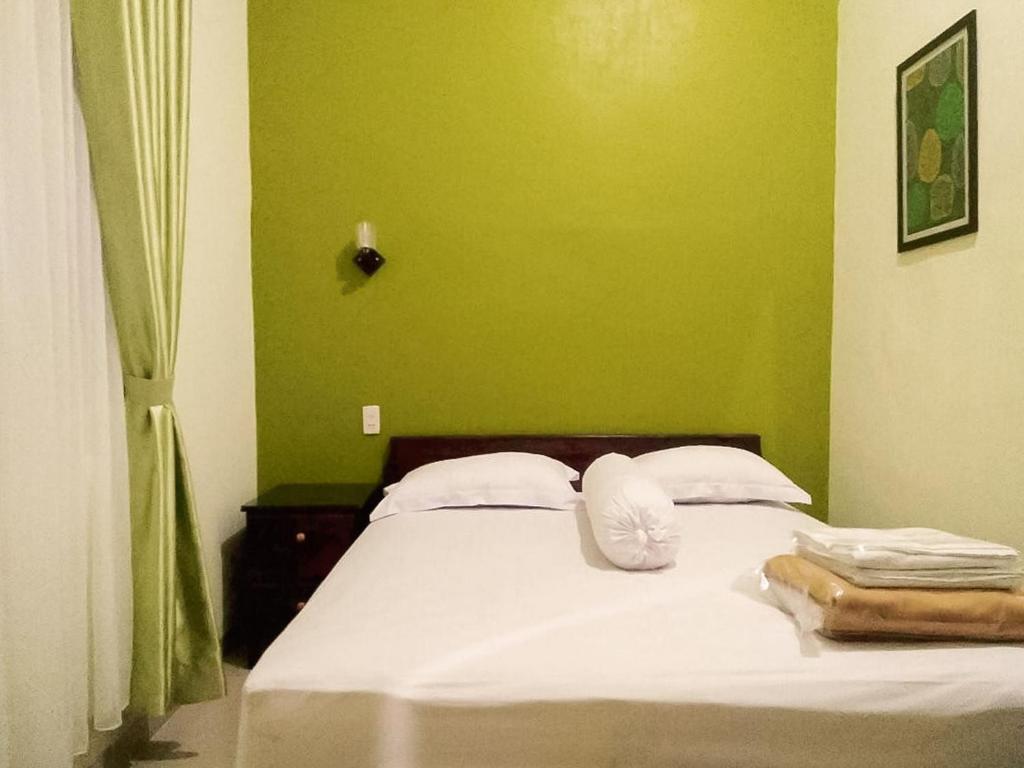 1 dormitorio con cama blanca y pared verde en RedDoorz near Pantai Pandan Sibolga 2 en Halangan