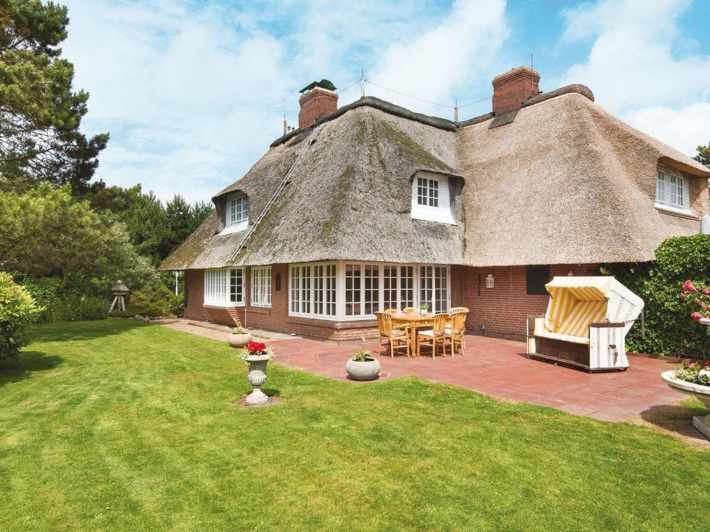 a thatch roofed house with a patio and a yard at Frederikenhof in Kampen