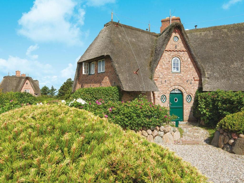 an old brick house with a green door on a hill at Hortensienhues-West in Kampen