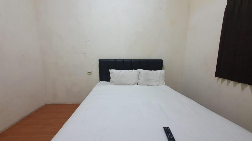 a white bed with a black headboard in a room at RedDoorz Syariah At Demasto Homestay Jember in Jember