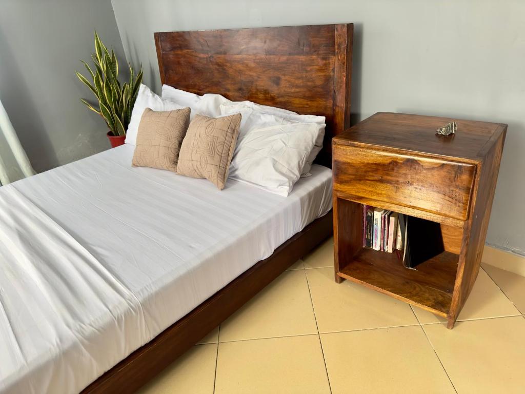 uma cama com uma cabeceira de madeira e uma mesa de madeira em Sally's home-near JNIA airport em Dar es Salaam