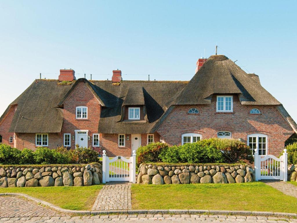 a large red brick house with a thatched roof at Prahl-Hues-2 in Kampen