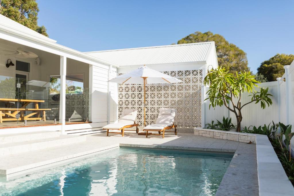 einen Pool mit zwei Stühlen und einem Sonnenschirm neben einem Haus in der Unterkunft White House Swan Hill in Swan Hill