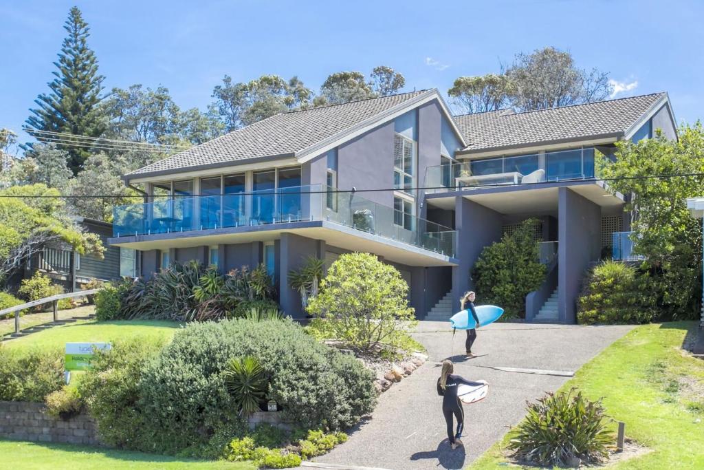 two people walking in front of a house with surfboards at Surfers Reef Escape Mollymook in Mollymook