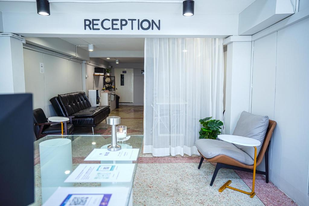 a living room with chairs and a table and a sign that reads reception at PICCOLO SUKHUMVIT HOSTEL in Bangkok